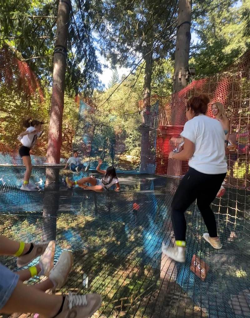 Niños y adultos en un parque de redes entre los árboles