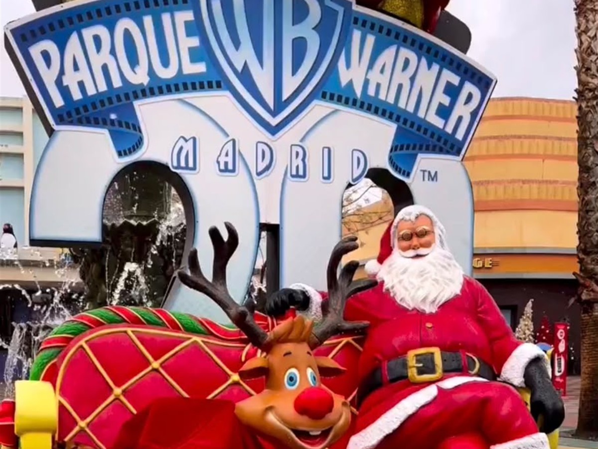 Papá Noel y un reno junto al cartel de Parque Warner Madrid decorado por Navidad
